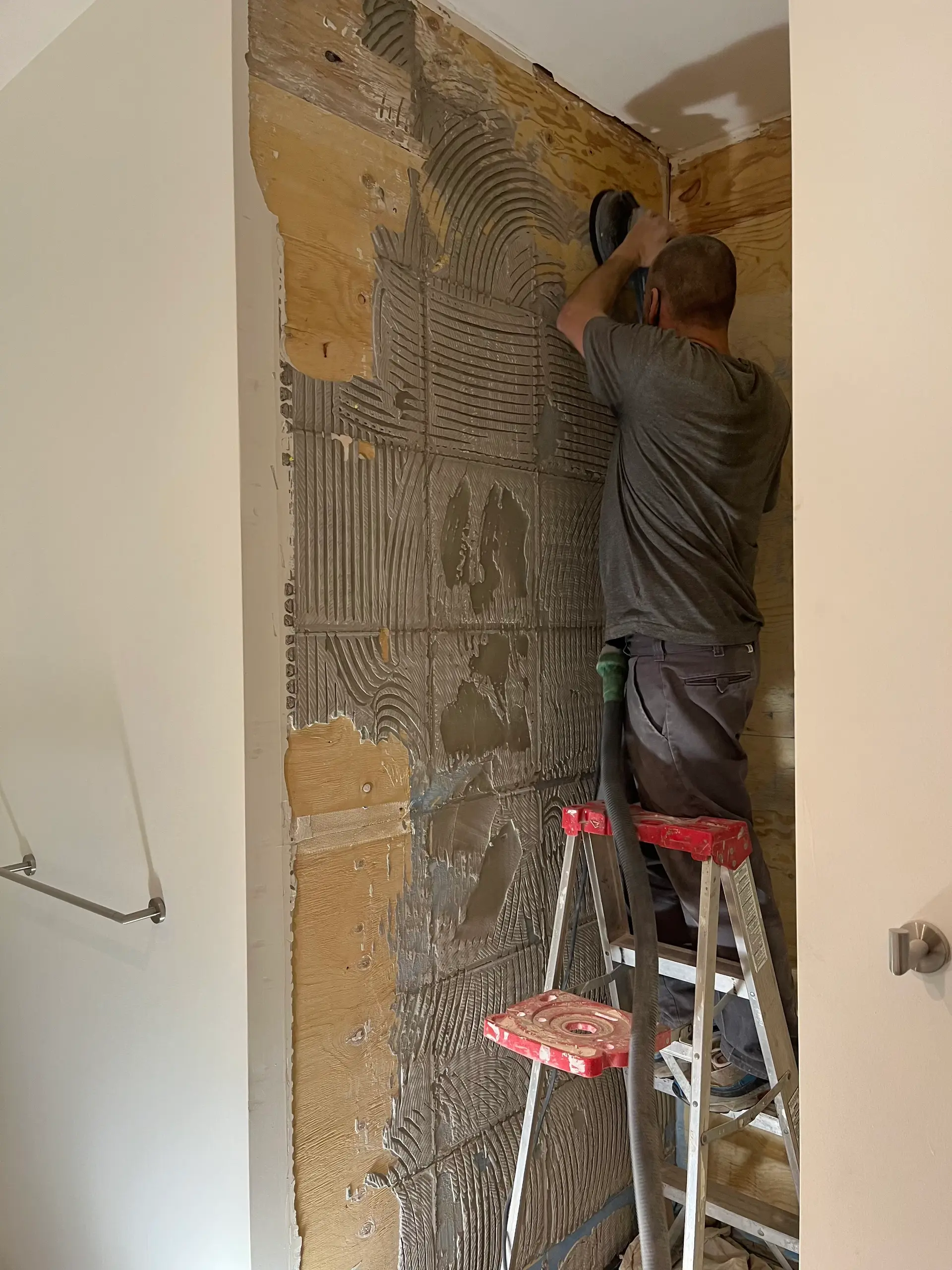 Wall tile installation with thinset mortar application on shower wall during bathroom renovation