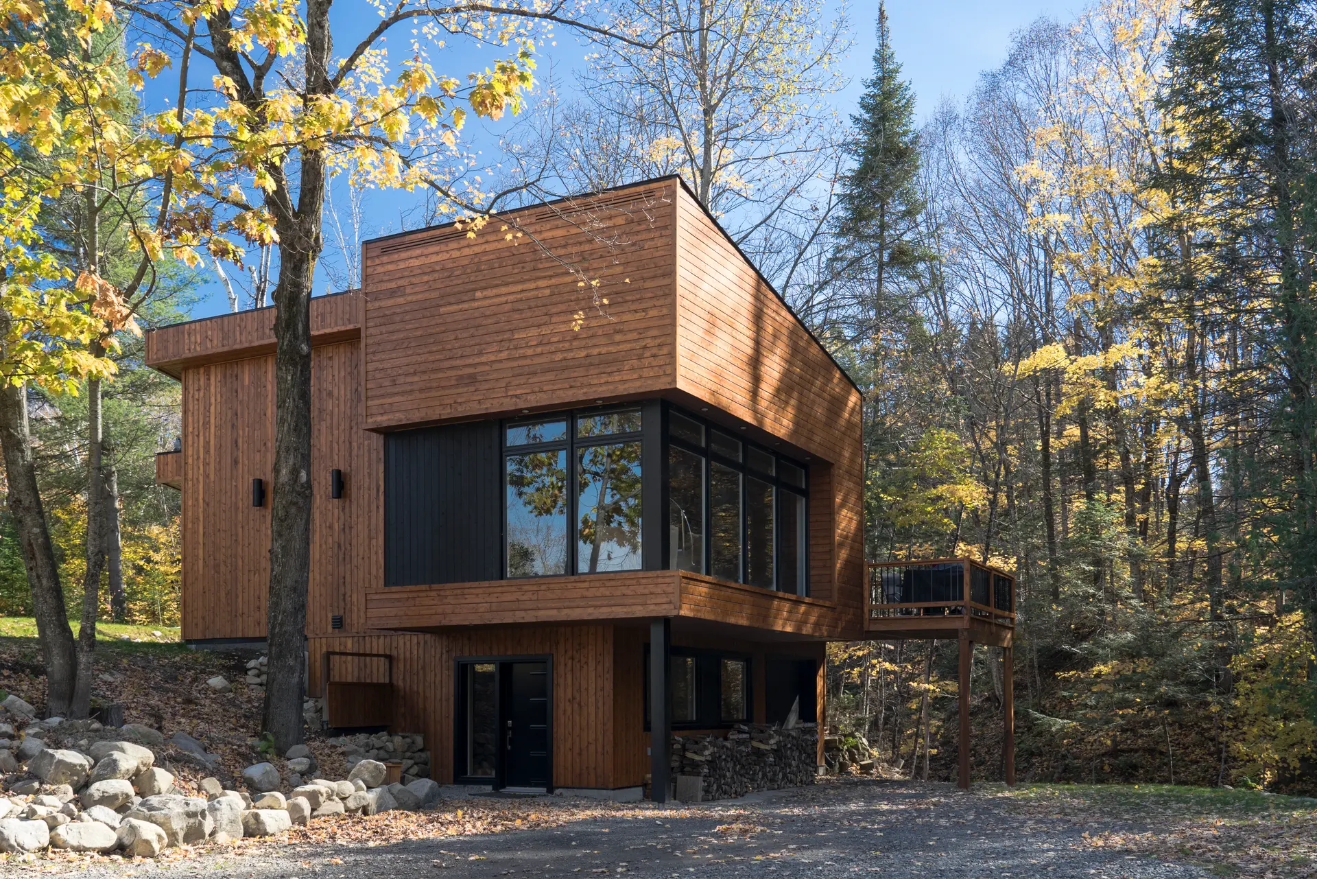 Modern wooden house in a forest during autumn with large windows and elevated deck
