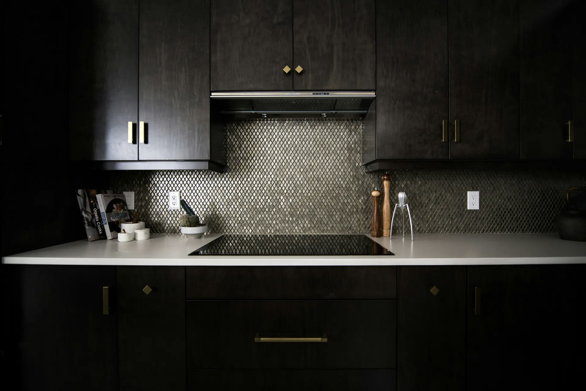 Modern kitchen with black cabinets, metal mosaic backsplash and white countertop