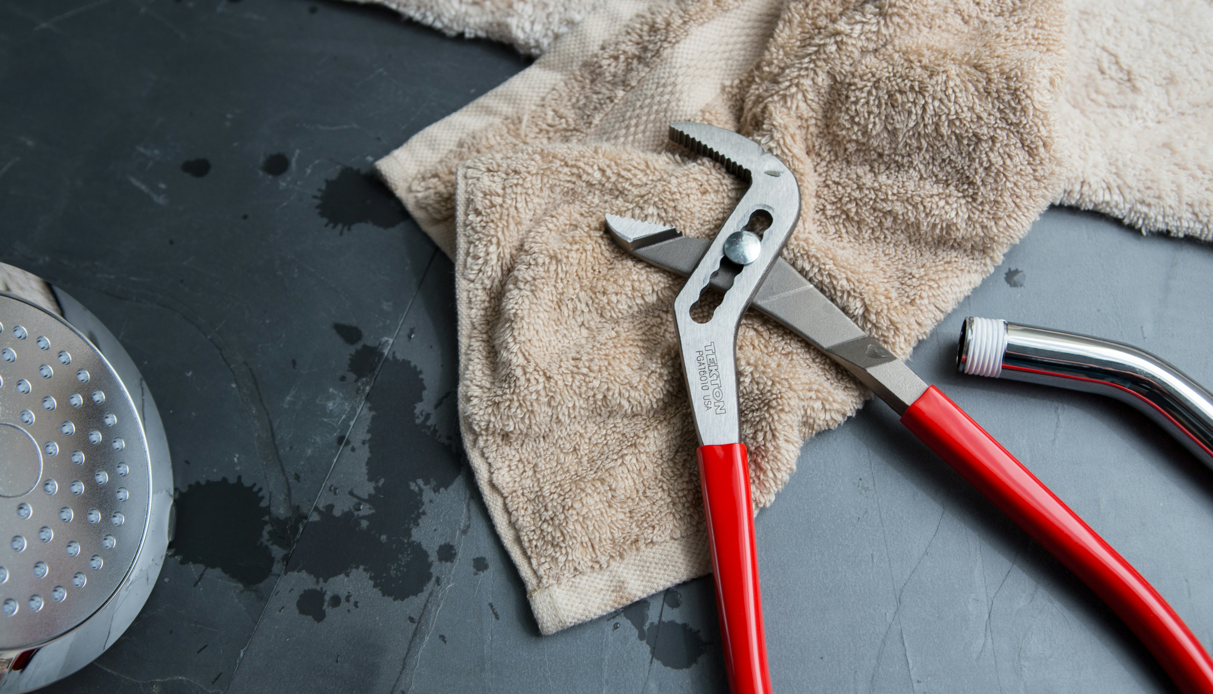 Red plumbing clamp placed on a towel with shower head and chrome hose
