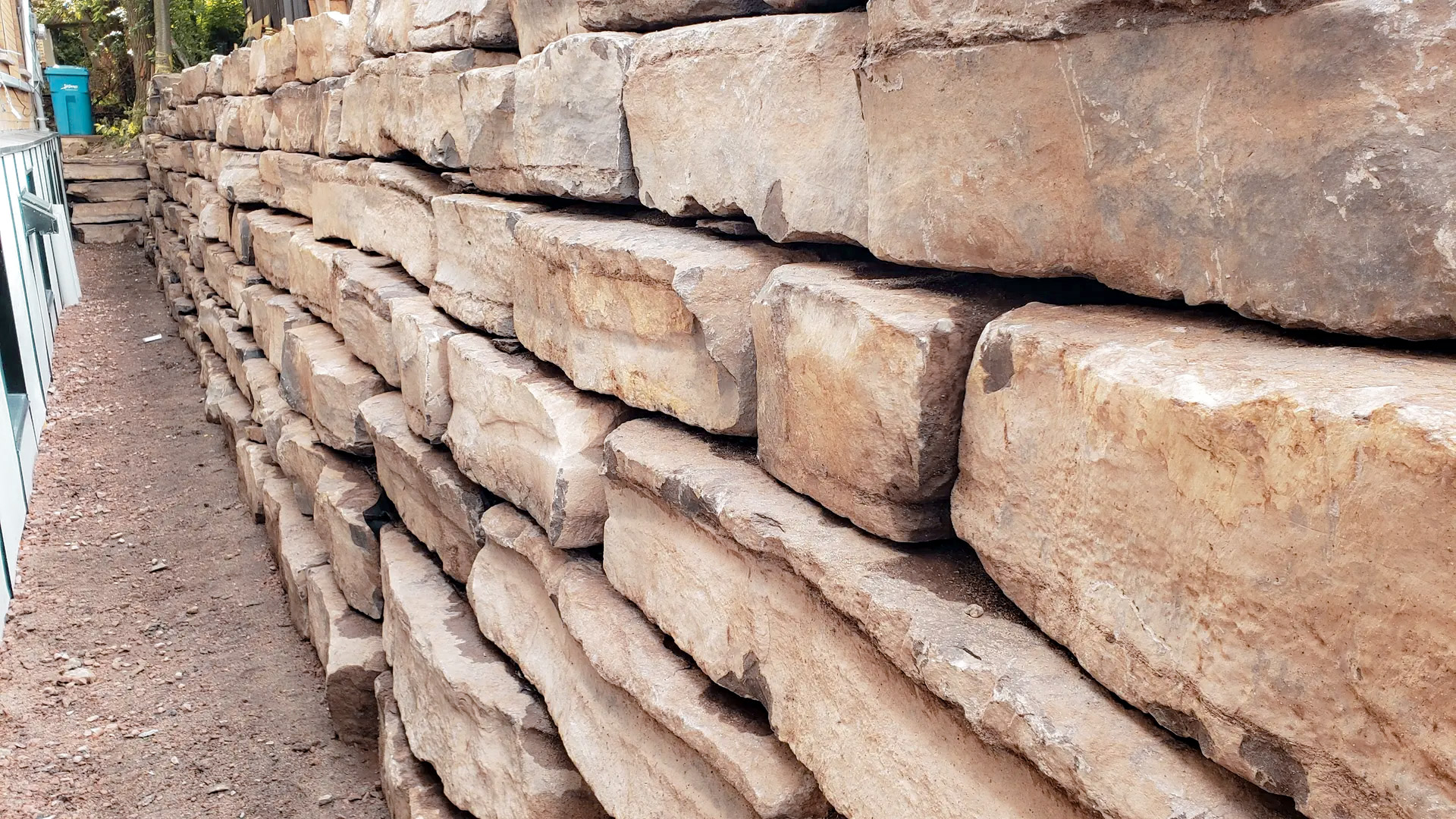 Natural stone retaining wall stacked along a residential building
