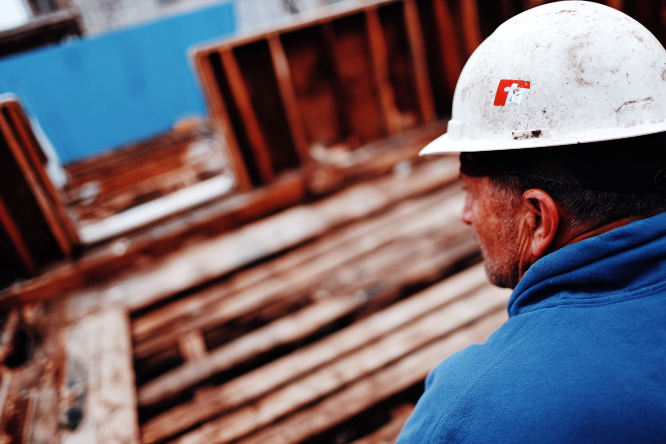 Ouvrier en casque de chantier observant une structure en bois en cours de construction