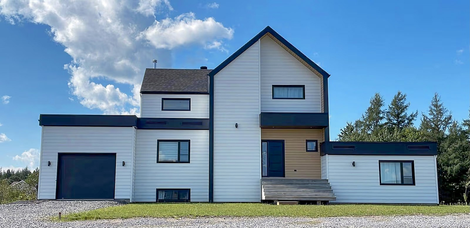 Maison moderne à deux étages avec revêtement extérieur blanc et accents noirs, garage intégré et entrée surélevée