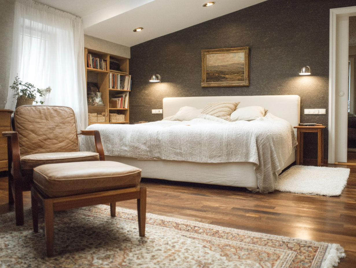 Cozy bedroom with double bed, leather armchair, wooden bookcase and wall lighting