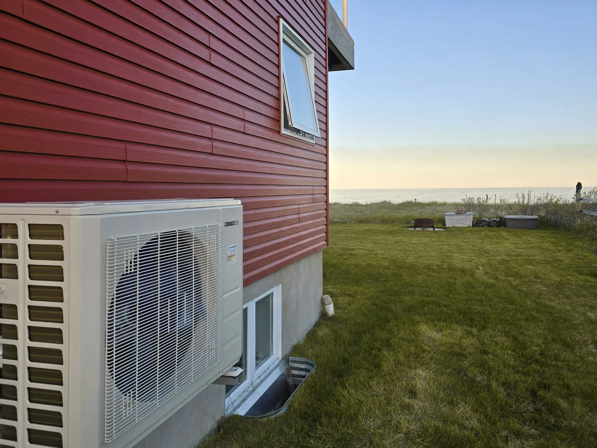 Samsung outdoor air conditioning unit with fan, facing a green garden and the ocean
