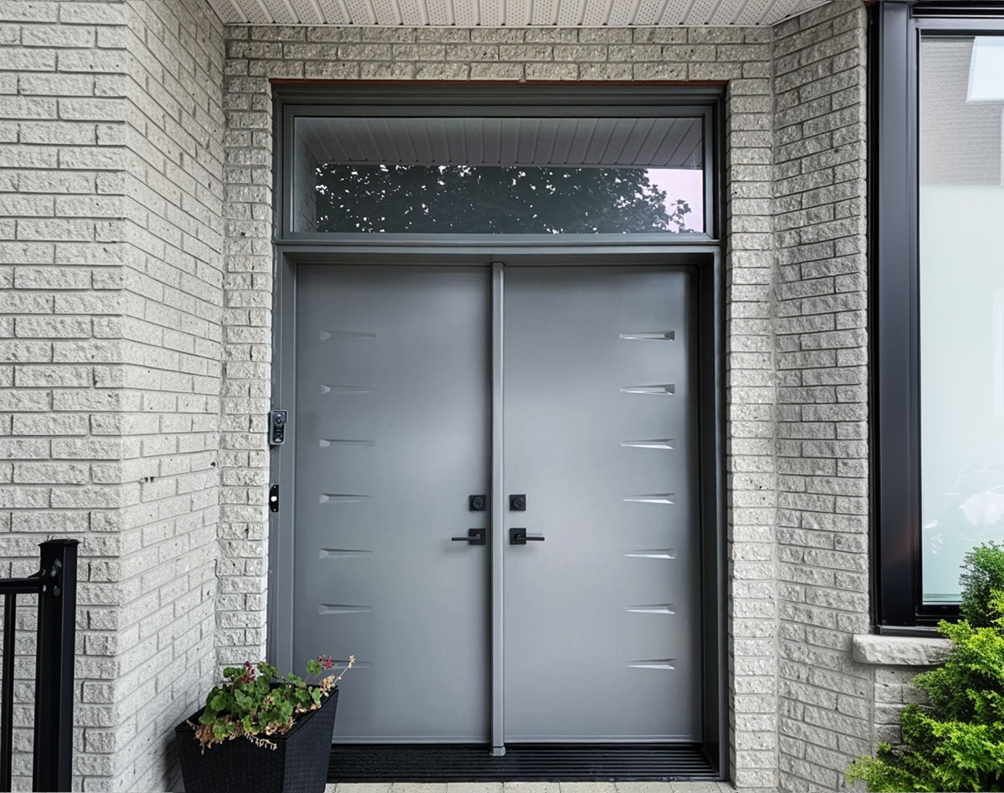 Modern double aluminum front door with black handles and an upper glass panel in a contemporary home.